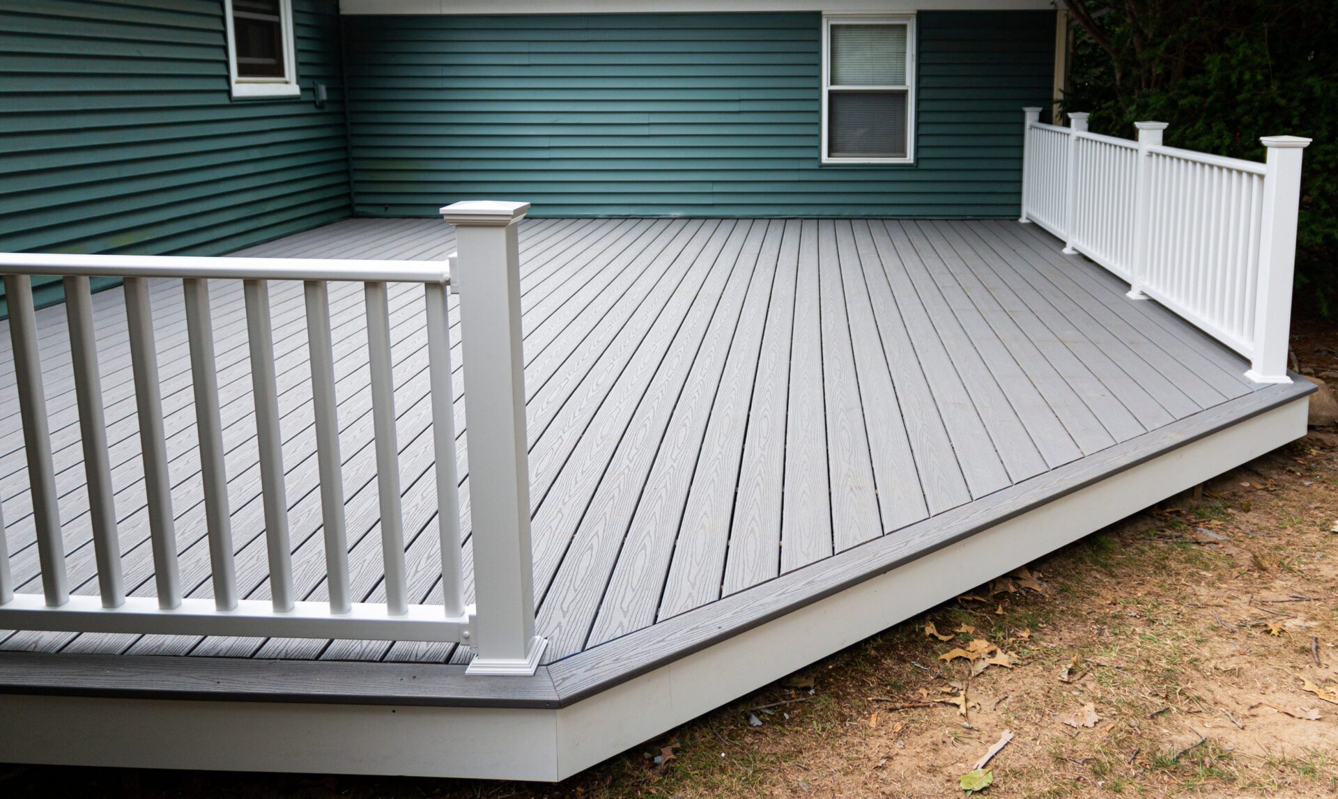 New composite deck on the back of a house with green vinyl siding New composite deck on the back of a house with green vinyl siding