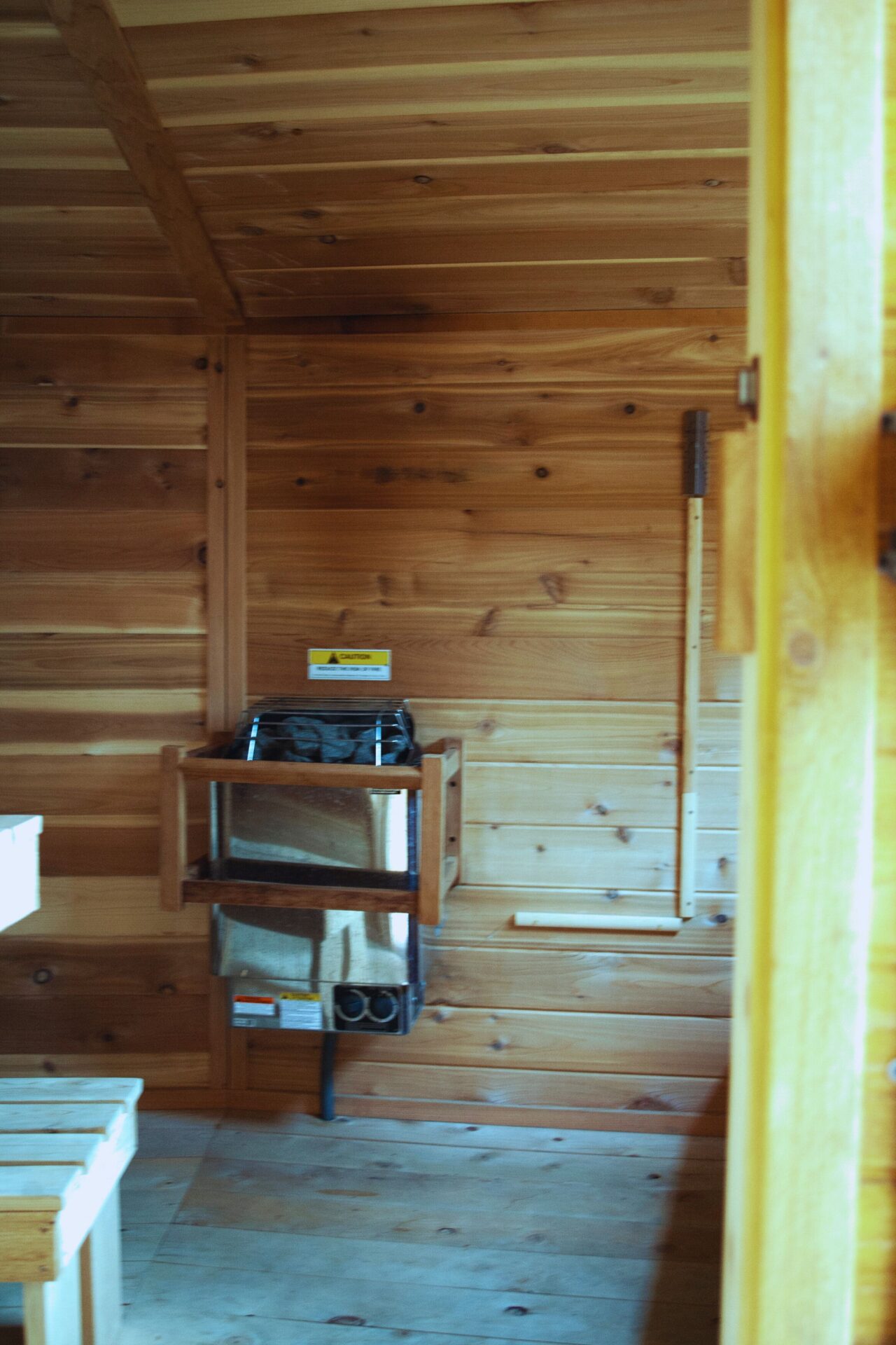 Interior view of custom wood sauna at Happy Hill Yurt featuring heater and bench seating.