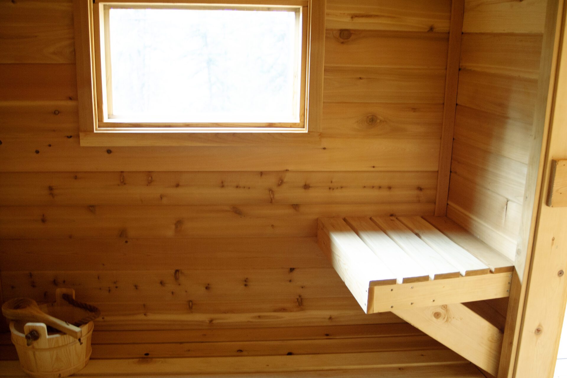 Wood-lined sauna interior with built-in bench seating at Happy Hill Yurt.