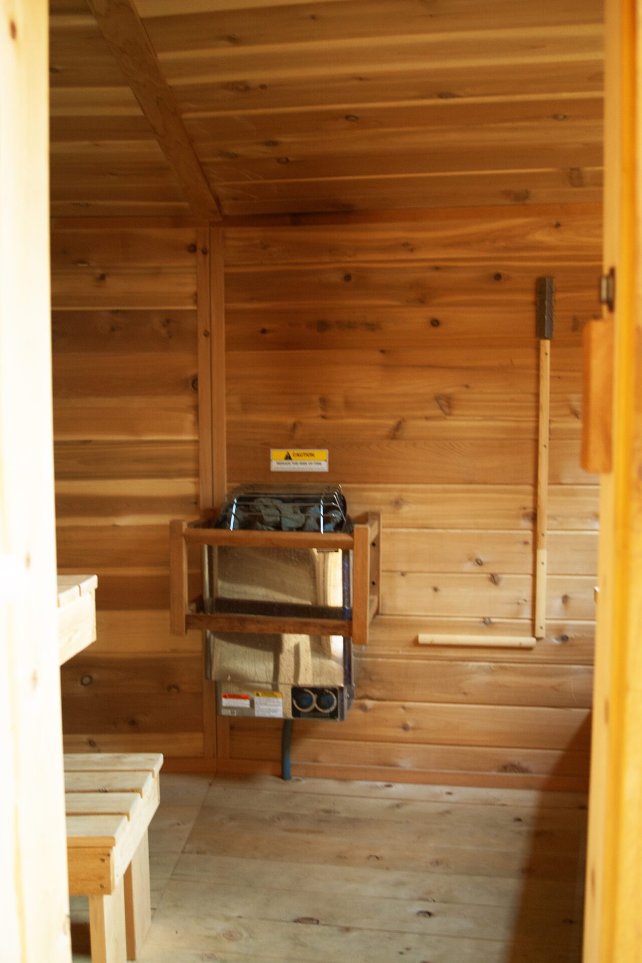 Interior view of custom wood sauna at Happy Hill Yurt featuring heater and bench seating.