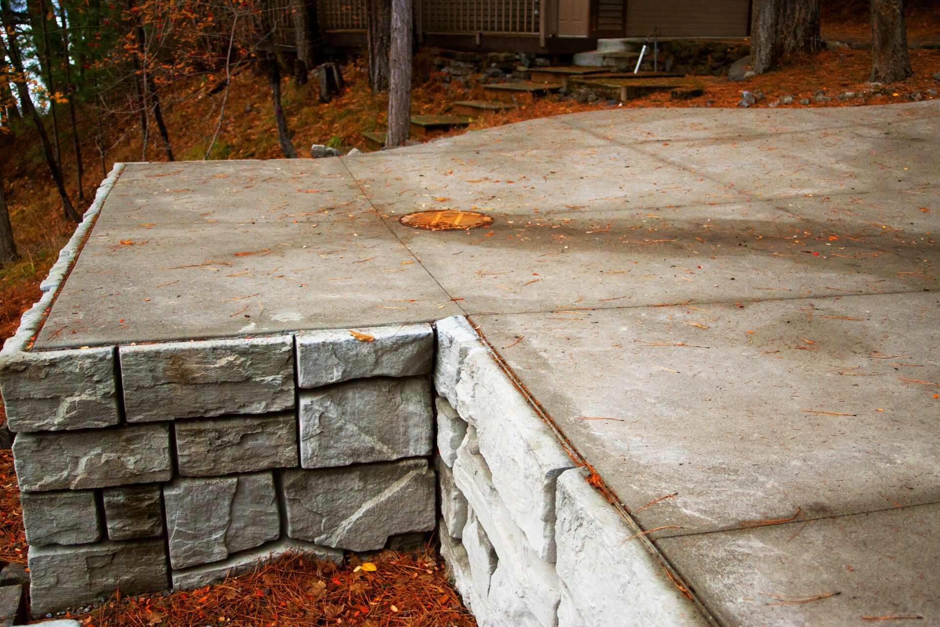 Concrete patio with custom stone retaining wall installed in Stanton by Blue Sky Decks hardscape team.